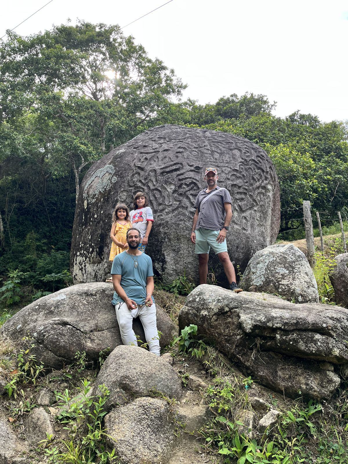 Personas junto a la gran roca de la Piedra de Donama, entre la vegetación de la Sierra